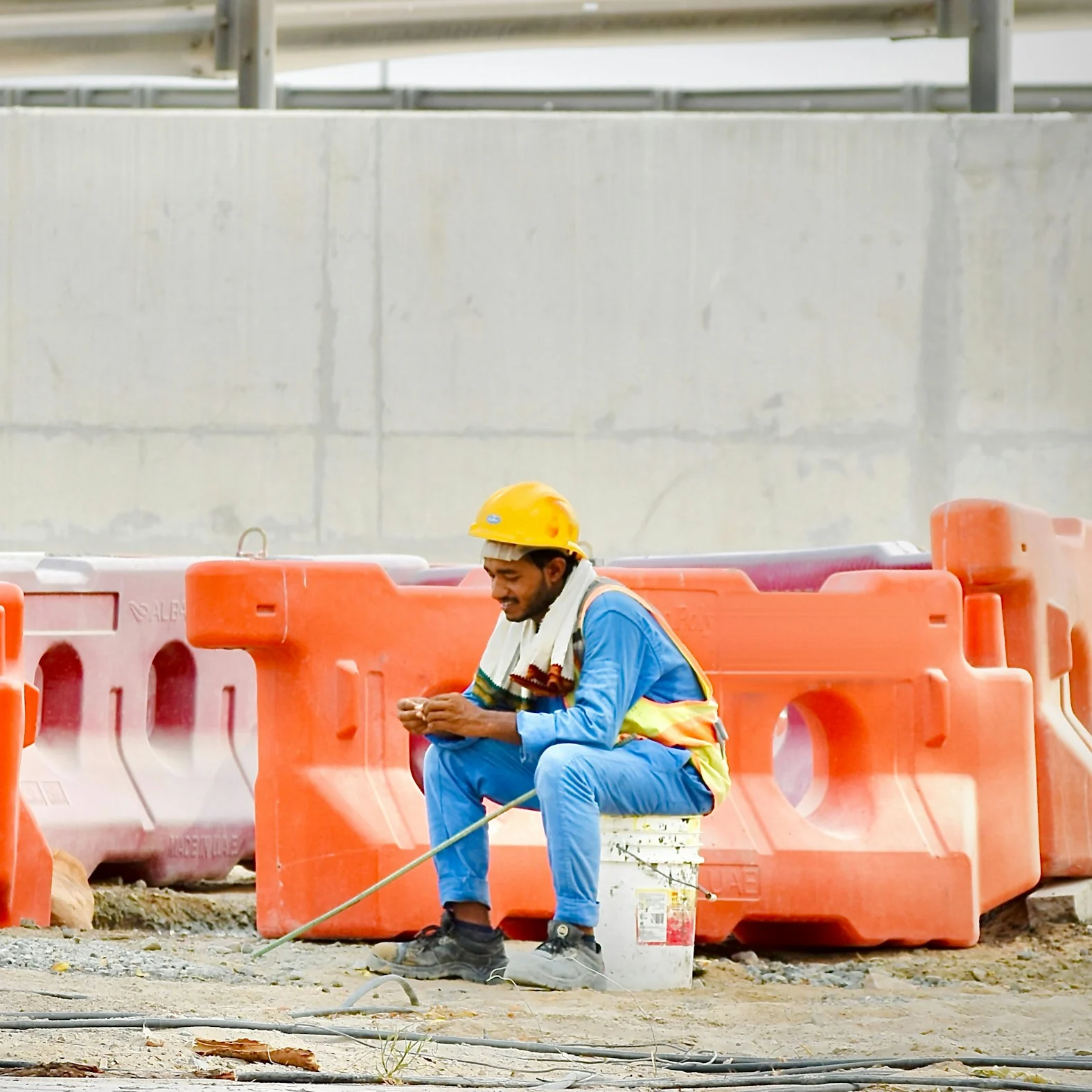 A construction worker in a hard hat taking a break among site barriers in Dubai