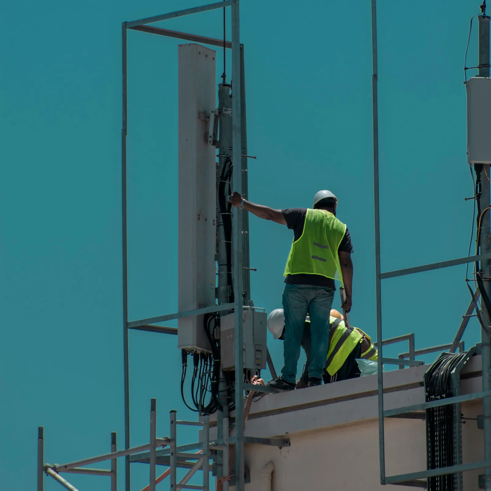 Technicians in safety vests installing equipment on a rooftop in Dubai