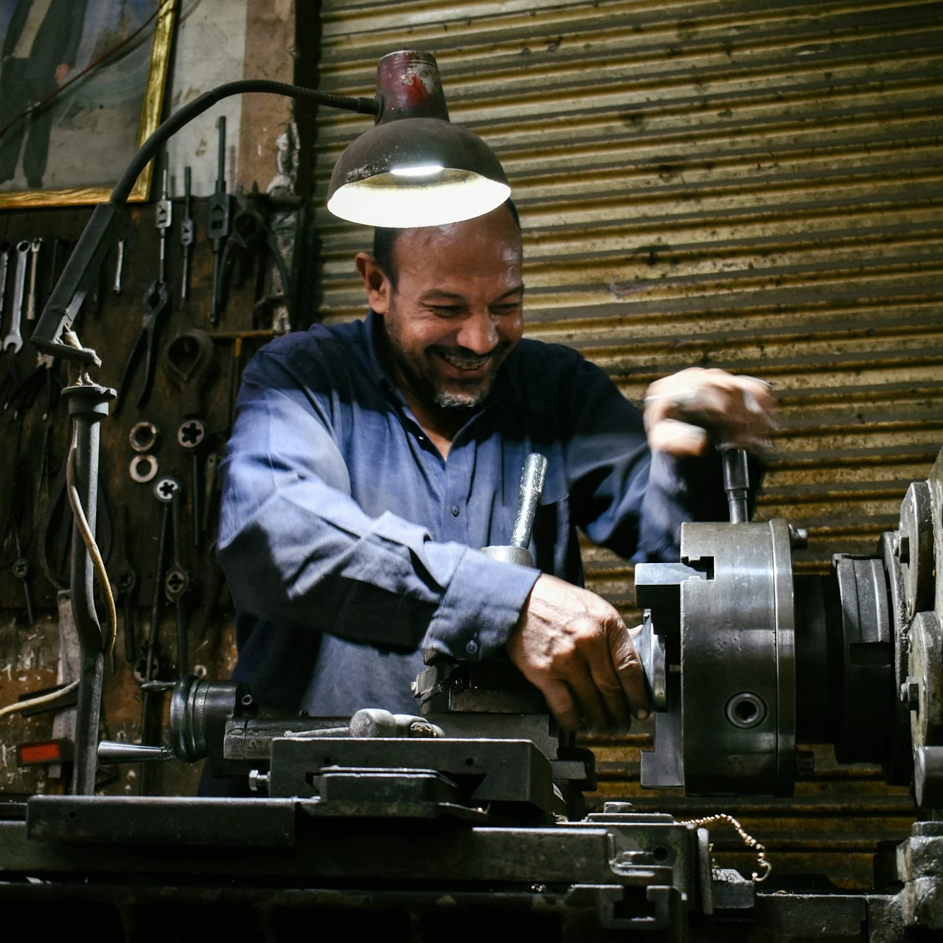 A machinist smiling as he works a lathe in his workshop in Egypt